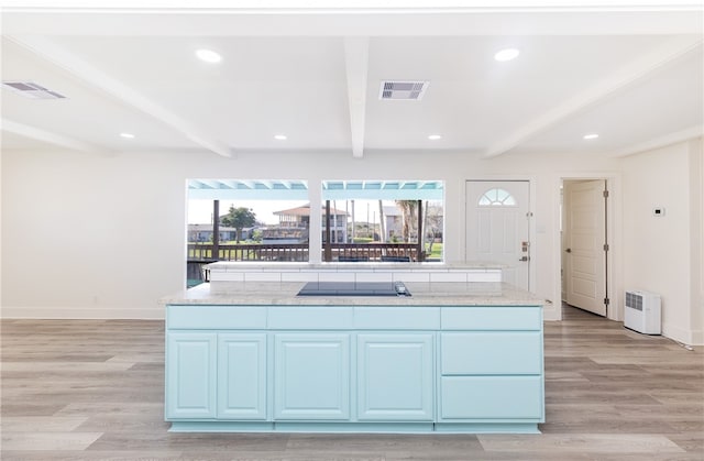 kitchen with light hardwood / wood-style floors, beamed ceiling, and a center island