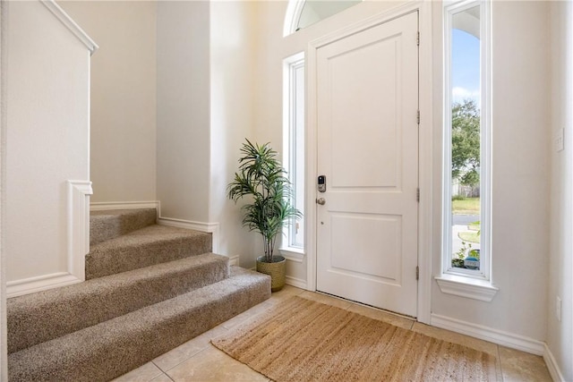 entrance foyer with stairs, baseboards, and light tile patterned flooring