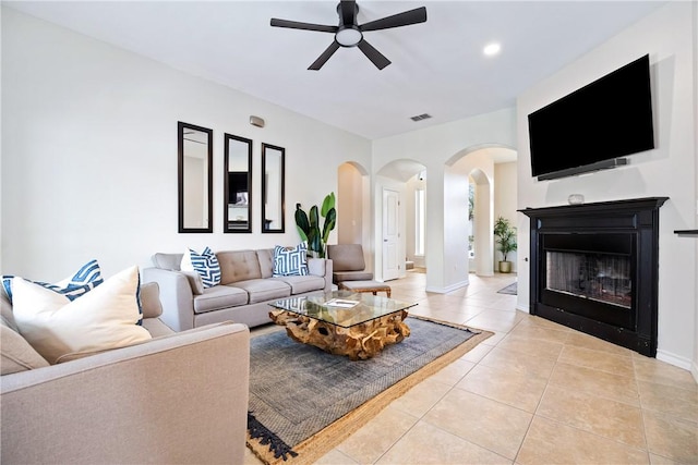 living room with baseboards, visible vents, a ceiling fan, a fireplace, and light tile patterned flooring