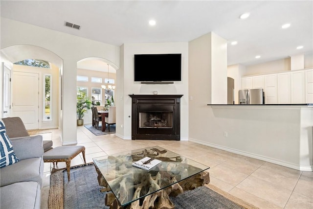 living area with light tile patterned floors, visible vents, arched walkways, and recessed lighting