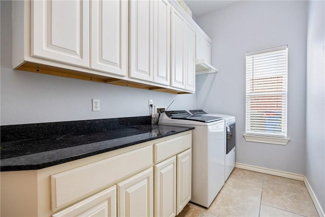 laundry area featuring light tile patterned flooring, washing machine and dryer, cabinet space, and baseboards