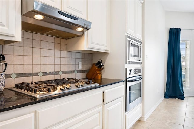 kitchen with light tile patterned floors, decorative backsplash, stainless steel appliances, under cabinet range hood, and white cabinetry