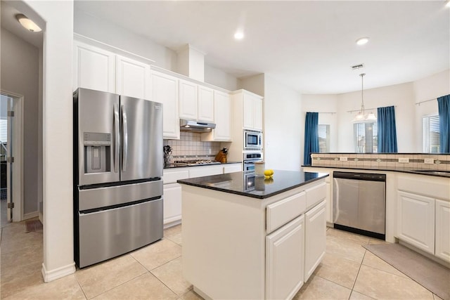 kitchen featuring under cabinet range hood, stainless steel appliances, a kitchen island, white cabinets, and backsplash