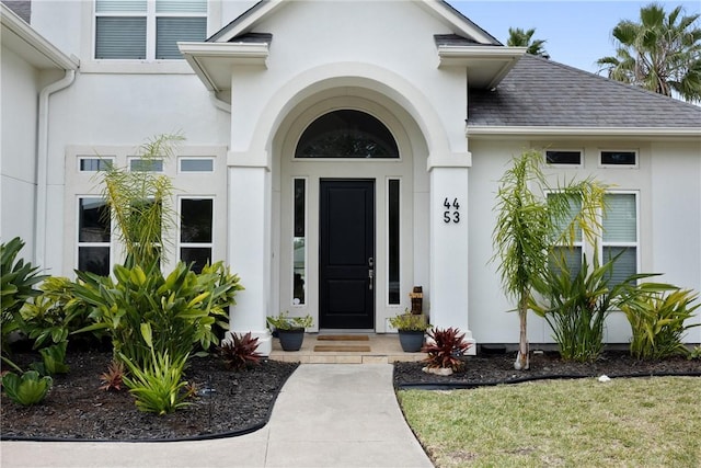 entrance to property with roof with shingles and stucco siding