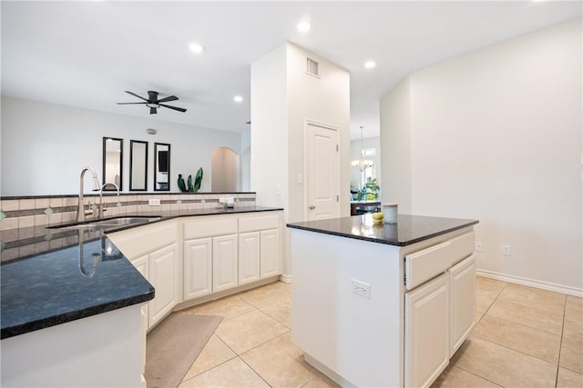 kitchen with a center island, tasteful backsplash, visible vents, a ceiling fan, and a sink