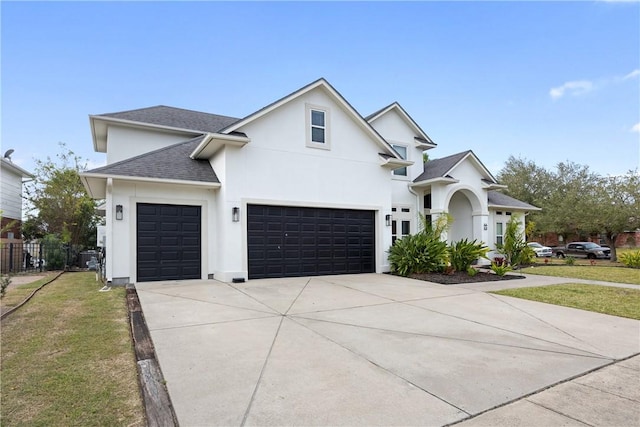 view of front facade featuring driveway, roof with shingles, fence, a front lawn, and stucco siding