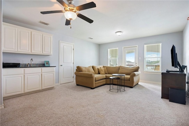 living room with visible vents, baseboards, light colored carpet, ceiling fan, and indoor wet bar