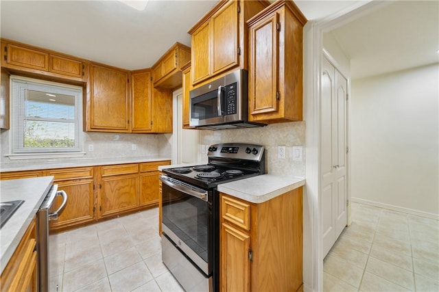 kitchen with light tile patterned flooring, brown cabinets, and appliances with stainless steel finishes