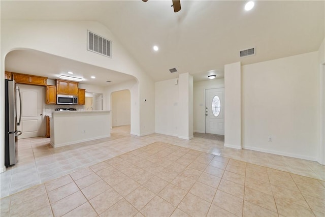 unfurnished living room featuring light tile patterned flooring, visible vents, arched walkways, and a ceiling fan
