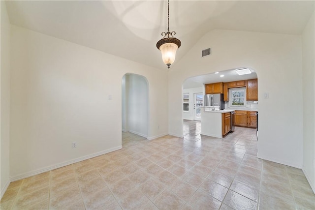 unfurnished living room with visible vents, baseboards, arched walkways, vaulted ceiling, and light tile patterned floors