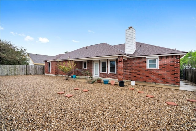 rear view of property with a patio area, a chimney, fence, brick siding, and a shingled roof