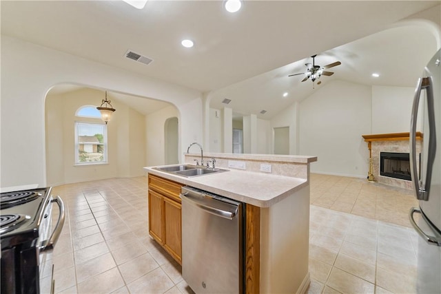 kitchen with a sink, appliances with stainless steel finishes, open floor plan, arched walkways, and ceiling fan