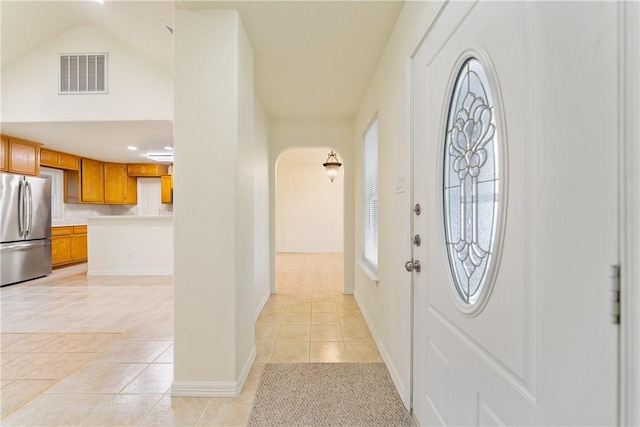 foyer featuring arched walkways, baseboards, visible vents, and light tile patterned flooring