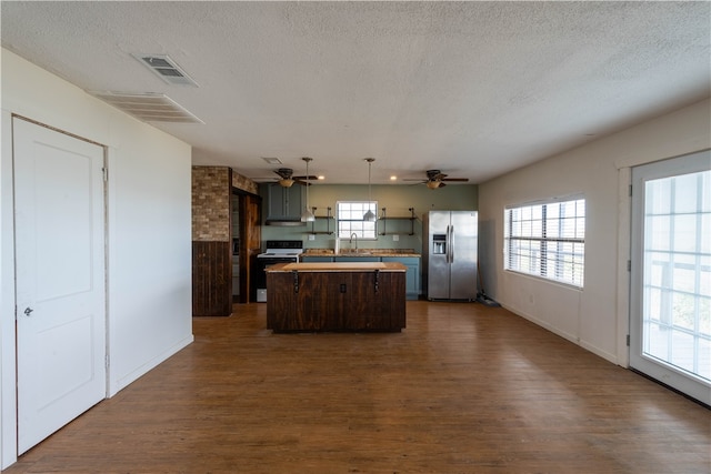 kitchen with stainless steel appliances, dark hardwood / wood-style floors, a textured ceiling, and a center island