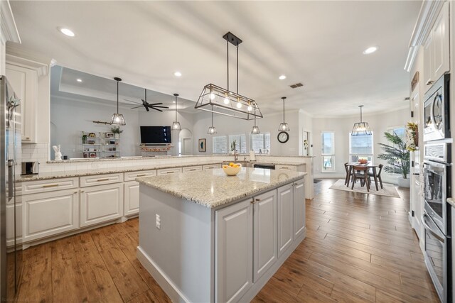 kitchen featuring a center island, open floor plan, white cabinetry, and decorative light fixtures