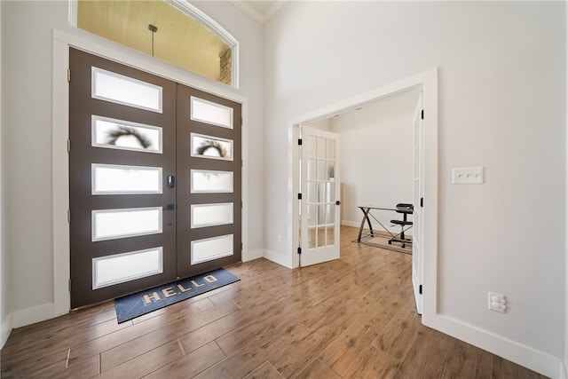 entrance foyer featuring crown molding, baseboards, wood finished floors, and french doors