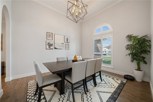 dining space with arched walkways, crown molding, an inviting chandelier, wood finished floors, and baseboards