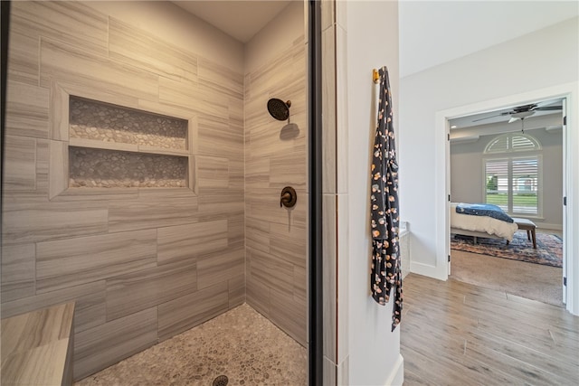 ensuite bathroom featuring wood finished floors, tiled shower, baseboards, and ensuite bathroom