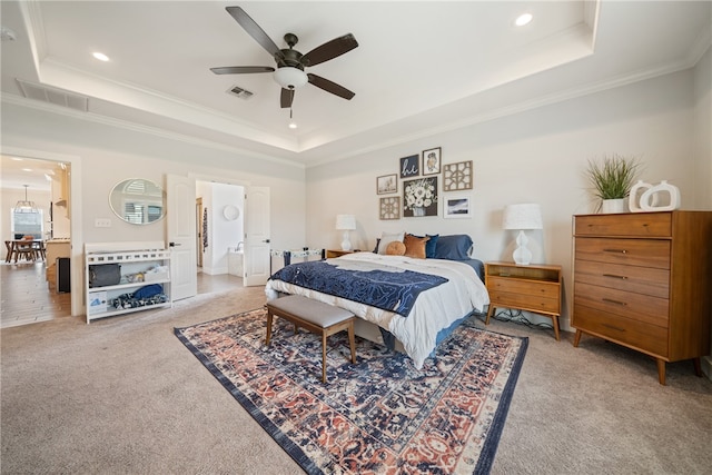 bedroom with a tray ceiling, visible vents, and carpet