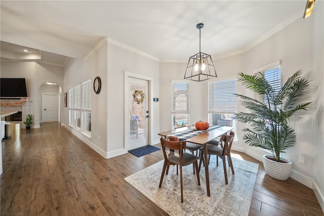 dining space with arched walkways, ornamental molding, dark wood-style flooring, and baseboards