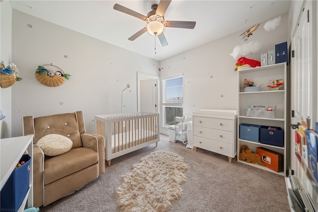 bedroom with a crib, a ceiling fan, and light colored carpet