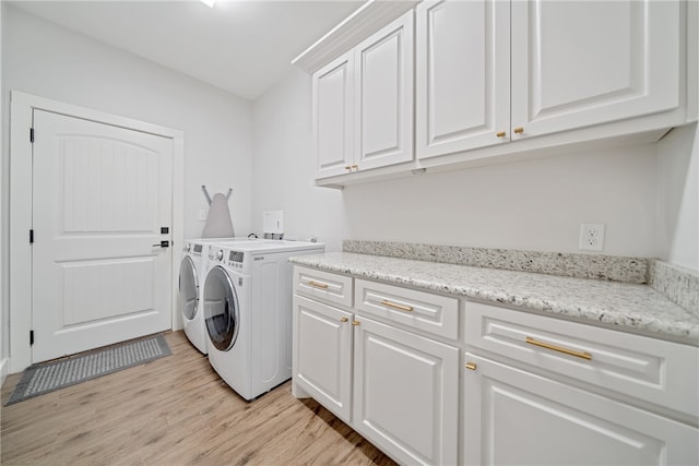 clothes washing area with light wood-type flooring, washing machine and dryer, and cabinet space