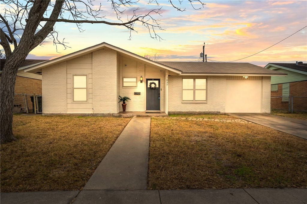 ranch-style house featuring a garage and a yard