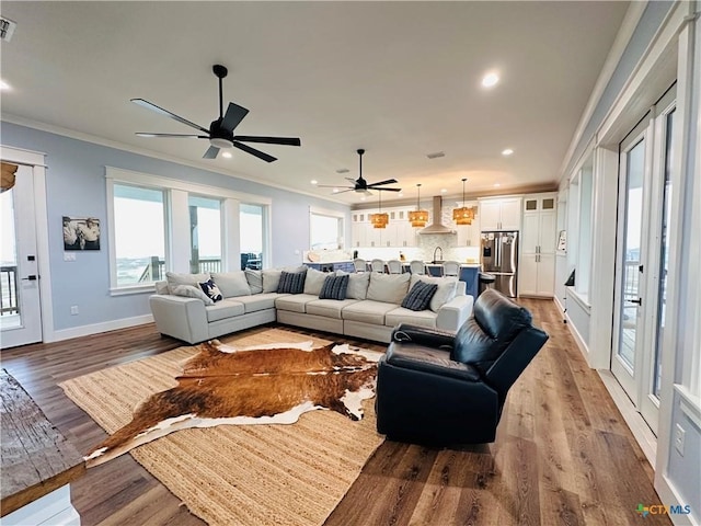 living room with wood-type flooring, ornamental molding, and ceiling fan