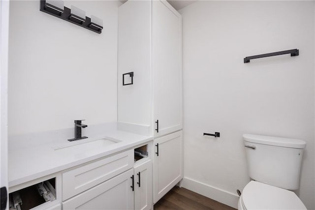 bathroom with hardwood / wood-style flooring, vanity, and toilet