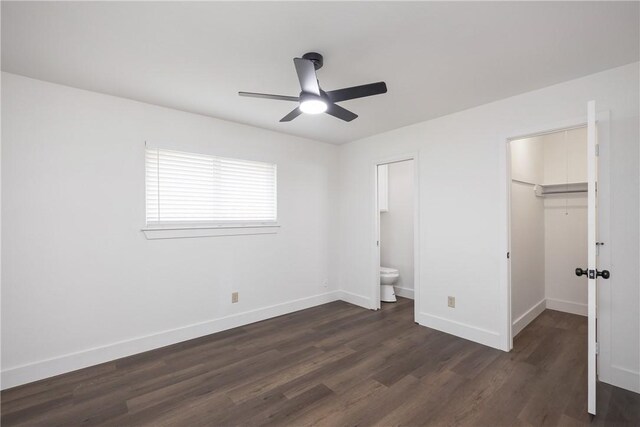 unfurnished bedroom featuring ceiling fan, dark hardwood / wood-style floors, a walk in closet, and ensuite bathroom