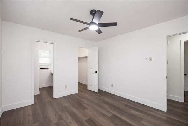 unfurnished bedroom featuring a closet, dark hardwood / wood-style floors, a spacious closet, and ceiling fan