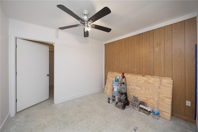 unfurnished bedroom with ceiling fan and wood walls