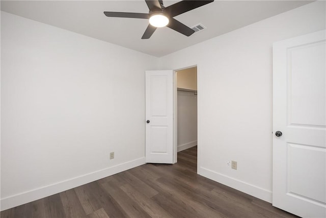 unfurnished bedroom featuring a closet, dark hardwood / wood-style floors, a spacious closet, and ceiling fan