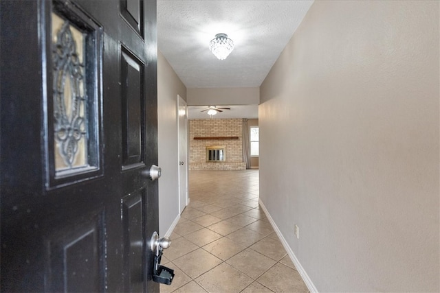 corridor with light tile patterned flooring, a textured ceiling, and brick wall