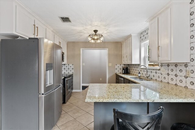 kitchen featuring kitchen peninsula, light stone countertops, stainless steel appliances, sink, and white cabinets