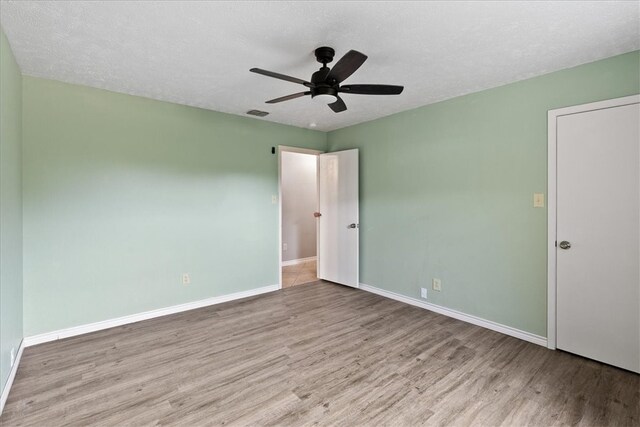 unfurnished room with ceiling fan, light hardwood / wood-style floors, and a textured ceiling