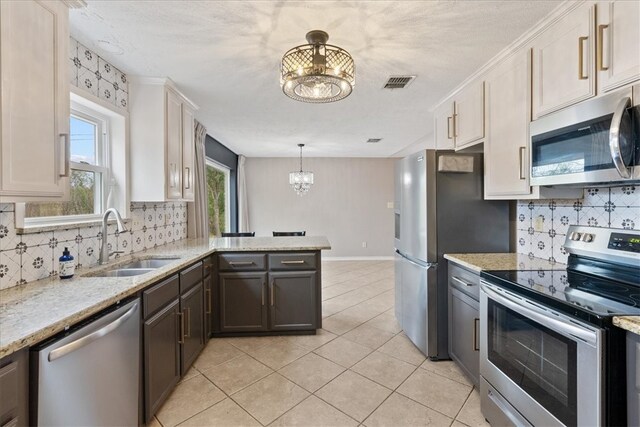 kitchen featuring white cabinets, sink, tasteful backsplash, decorative light fixtures, and stainless steel appliances