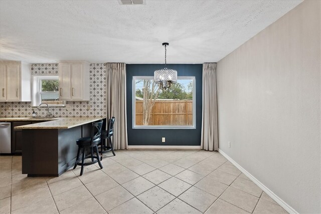 kitchen featuring a kitchen bar, a wealth of natural light, dishwasher, and decorative light fixtures