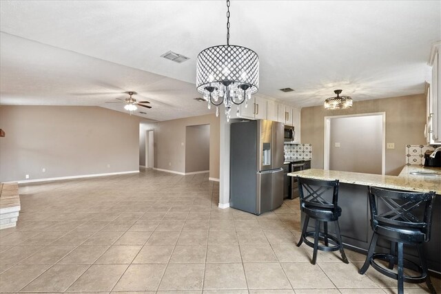 kitchen with white cabinets, ceiling fan with notable chandelier, a kitchen breakfast bar, light stone countertops, and appliances with stainless steel finishes