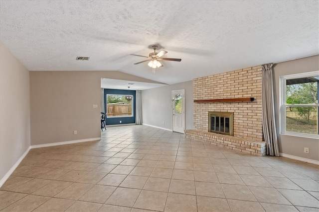 unfurnished living room featuring ceiling fan, a textured ceiling, vaulted ceiling, a fireplace, and light tile patterned floors