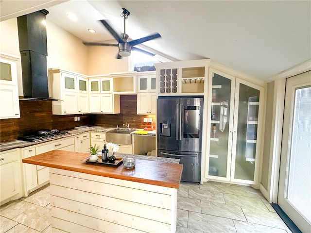 kitchen featuring decorative backsplash, appliances with stainless steel finishes, ventilation hood, sink, and butcher block countertops