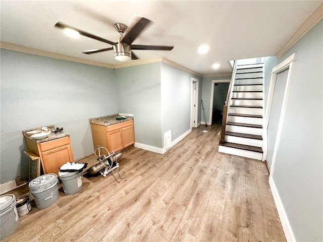 basement featuring ceiling fan, crown molding, and light hardwood / wood-style floors