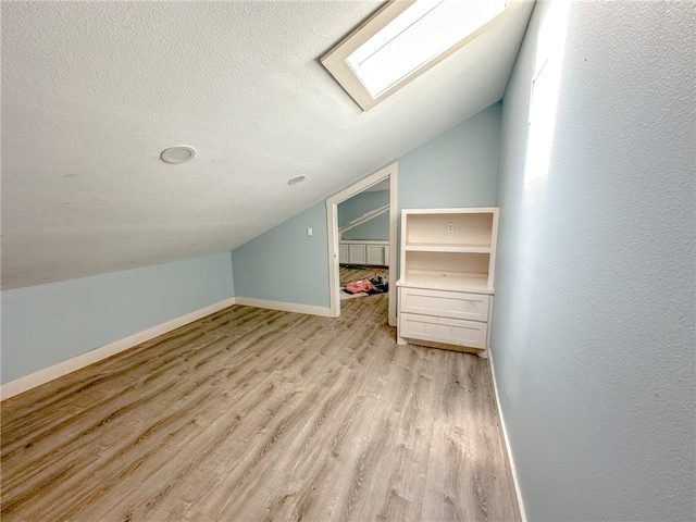 bonus room featuring light hardwood / wood-style floors and lofted ceiling with skylight