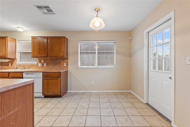 kitchen featuring decorative backsplash, white dishwasher, pendant lighting, and light tile patterned floors