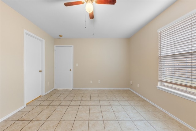 empty room with ceiling fan and light tile patterned flooring