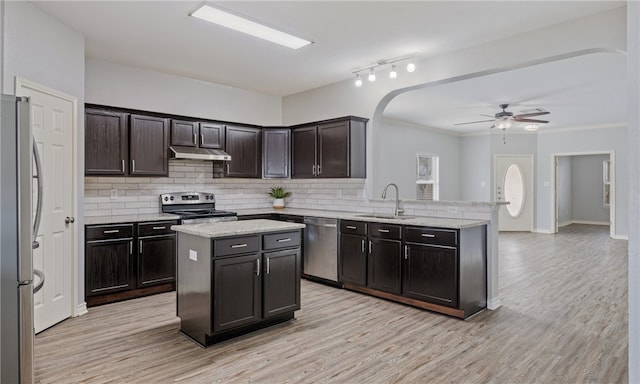 kitchen featuring tasteful backsplash, a peninsula, stainless steel appliances, under cabinet range hood, and a sink