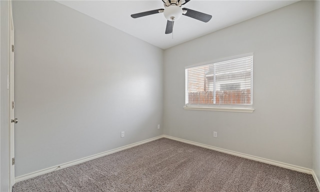 carpeted spare room with a ceiling fan and baseboards