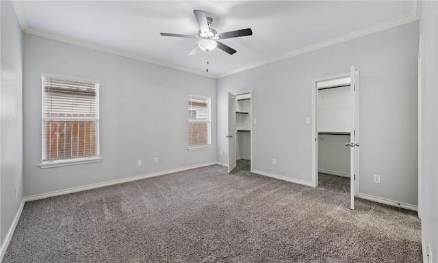 unfurnished bedroom featuring carpet floors, ornamental molding, a walk in closet, and baseboards