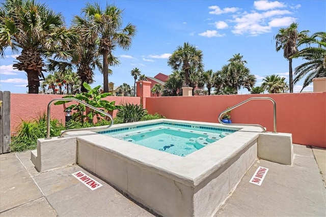 view of swimming pool with fence and a hot tub