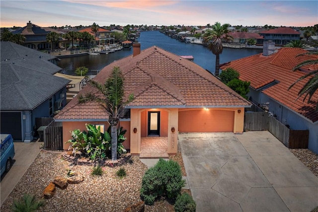 15929 San Felipe Dr, Corpus Christi, TX 78418 - view of front of home featuring concrete driveway, a garage, stucco siding, a water view, and a tile roof
